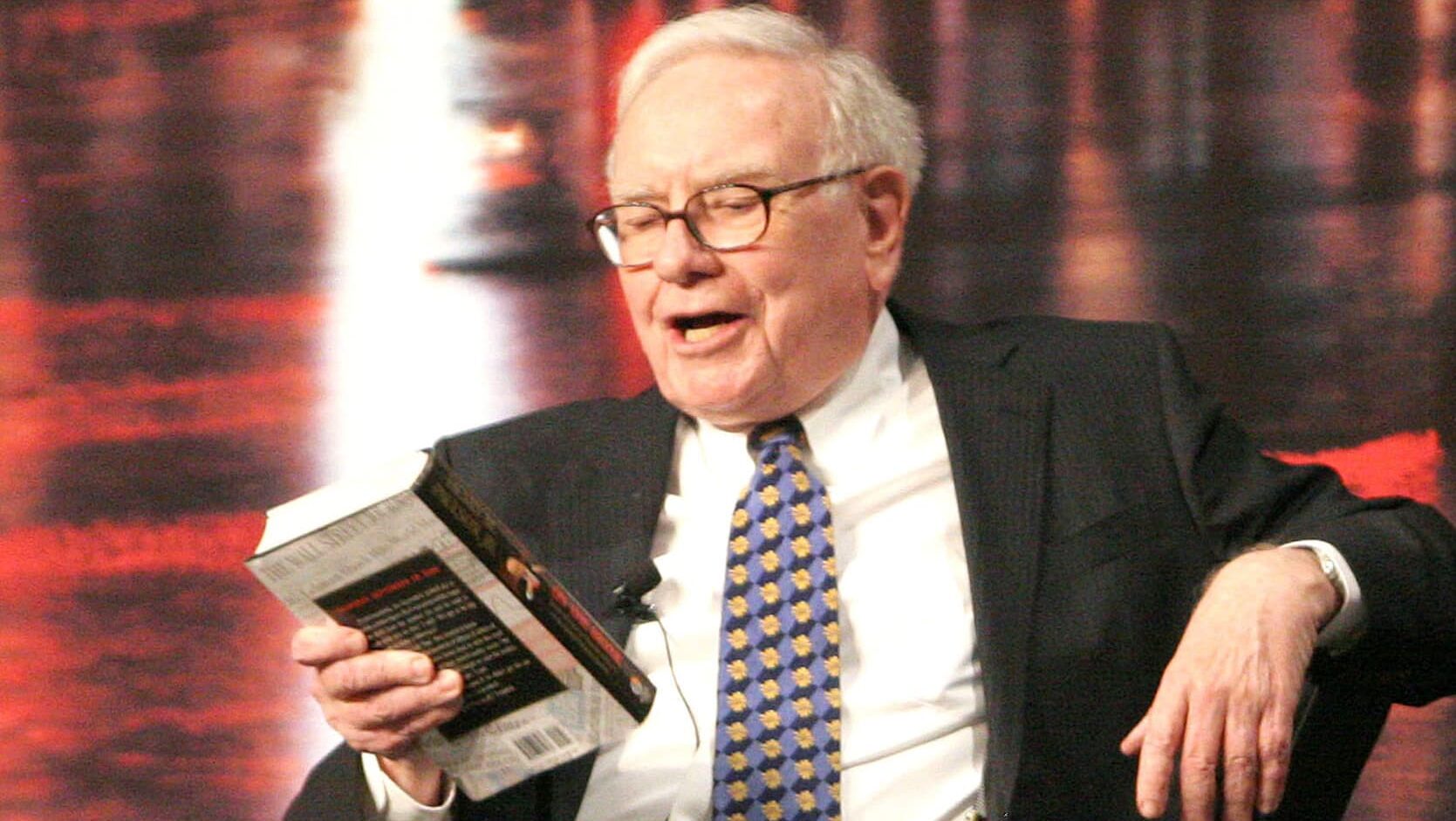 Investor legendaris Warren Buffet sedang membaca buku saham.