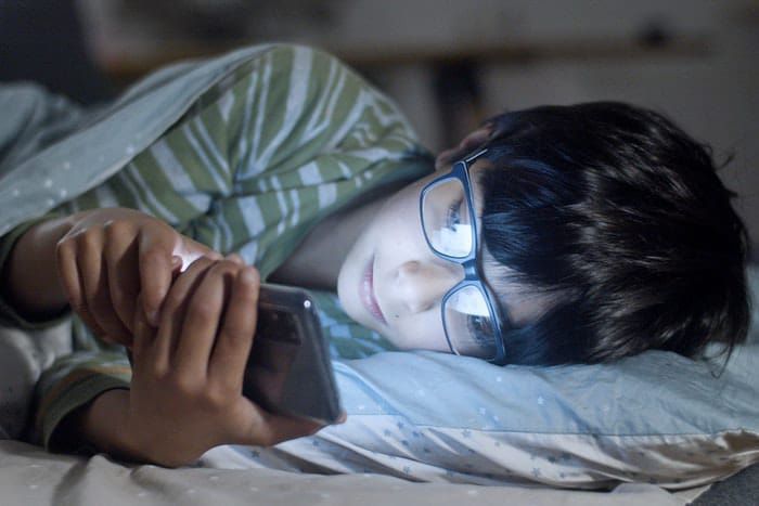 seorang wanita sedang main ponsel sebelum tidur 