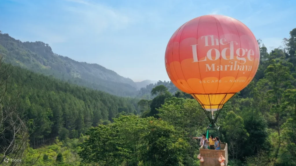 Pemandangan alam di The Lodge Maribaya dengan balon udara di latar belakang.
